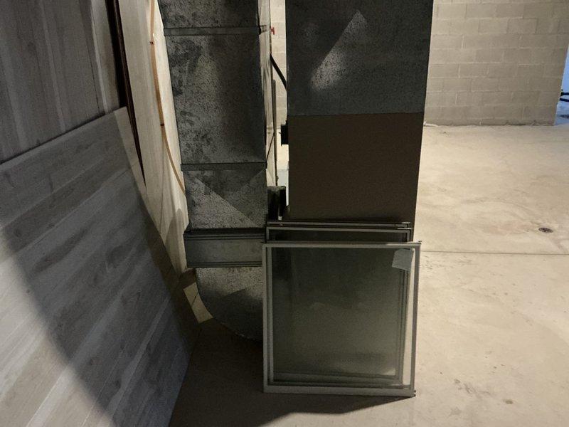 Completed comprehensive HVAC estimate for furnace and air conditioning replacement at duplex property. Assessed existing outdoor condenser unit showing weathering and age, along with associated electrical disconnect and gas meter configuration. Evaluated basement ductwork system including metal plenum and distribution components for compatibility with proposed replacement equipment.