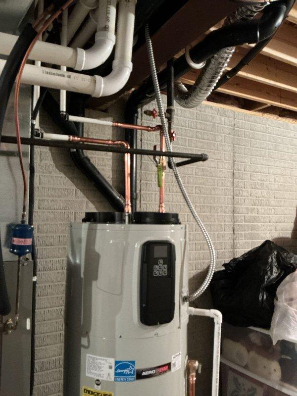 Removed existing electric water heater and installed new Bradford White heat pump water heater unit with Energy Star certification. Converted existing PEX water supply lines to copper piping during installation and installed non-metal water pan beneath unit. Verified proper connection to existing expansion tank located near water meter and confirmed all plumbing connections, electrical conduit, and PVC discharge lines are functioning correctly per manufacturer specifications.