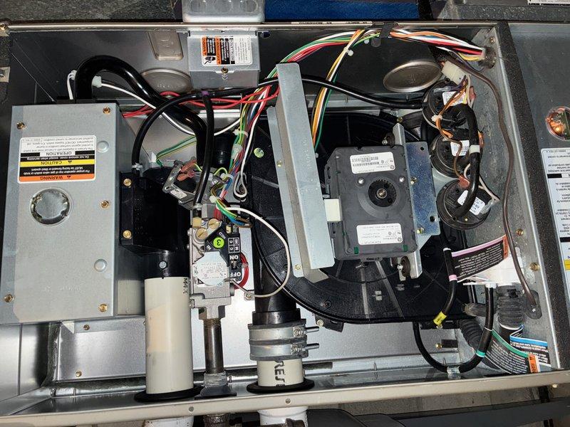 Performed complimentary air conditioning tune-up on system of unknown age. Inspected ductwork to assess cleaning needs and found standard accumulation of dust and debris throughout accessible sections. Examined air filter which showed moderate soiling with dark spots and staining across mesh surface, indicating normal use and particle capture. Removed access panels to inspect internal HVAC components including blower motor assembly, gas valve manifold, control box, and electrical connections. Verified all wiring connections were secure with proper routing of power and control wires. Confirmed blower motors and fan assemblies were operational with no unusual wear or noise detected. All system components appeared to be functioning within normal parameters at time of inspection.