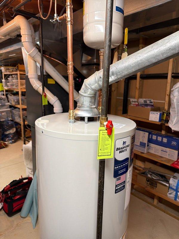 Installed a 40-gallon tall Bradford White water heater with expansion tank in basement utility area. Connected all supply and discharge lines including copper piping, installed 1/2x1/4 shut-off valve, and properly secured expansion tank above unit with copper loop connection. All connections tested and system operational.