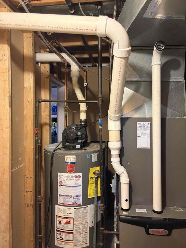 Diagnosed exhaust venting issue causing water to discharge in large quantities from furnace exhaust. Upon inspection, discovered that previous third-party rerouting of exhaust piping (performed to accommodate hot tub installation) created a 10-foot trap section with improper pitch, resulting in significant water accumulation. Determined that existing exhaust configuration violated proper venting standards and required correction. Identified that power vent water heater exhaust has identical improper pitch condition and will likely experience similar issues. Proposed two corrective solutions: reroute exhaust piping back to original configuration near hot tub location, or lower exhaust termination through finished basement wall into furnace room to achieve proper pitch and drainage. Customer approved repair work to be scheduled and completed by installation crew to ensure compliant venting system operation.