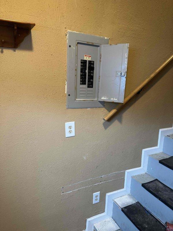 Completed AC circuit pre-wire installation over multiple site visits. Installed and configured main electrical panel in interior stairwell location, mounting breaker box with dual columns of circuit breakers and proper labeling. Established branch circuit wiring with outlet installations at appropriate wall heights below panel. Applied non-slip safety treads to stairwell steps in work area. Installed exterior disconnect box on building siding with ON/OFF switch mechanism, connecting service conductors through conduit entry. Terminated red, black, and green phase and ground wiring to terminal blocks with proper torque specifications. Routed flexible conduit from disconnect enclosure down exterior wall for service connection. All installations completed per NEC requirements with appropriate wire sizing and connection methods.