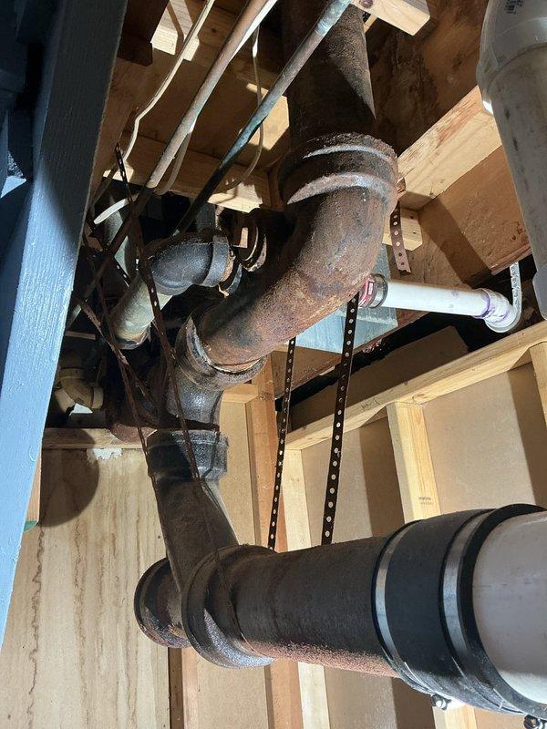 Responded to service call for replacement of deteriorated plumbing infrastructure serving two toilet installations. Upon inspection, found approximately 59-year-old cast iron and copper drain pipes exhibiting severe corrosion and surface deterioration throughout the waste line system. Removed sections of finished flooring to access subfloor plumbing components. Replaced corroded cast iron drain pipes and copper supply lines with code-compliant materials. Removed and replaced two toilet flanges that had deteriorated due to age and corrosion. Work required coordination with existing floor joist structure and HVAC ductwork in confined crawl space area. All replaced components installed to current plumbing code specifications to ensure proper drainage and structural integrity for toilet fixtures.