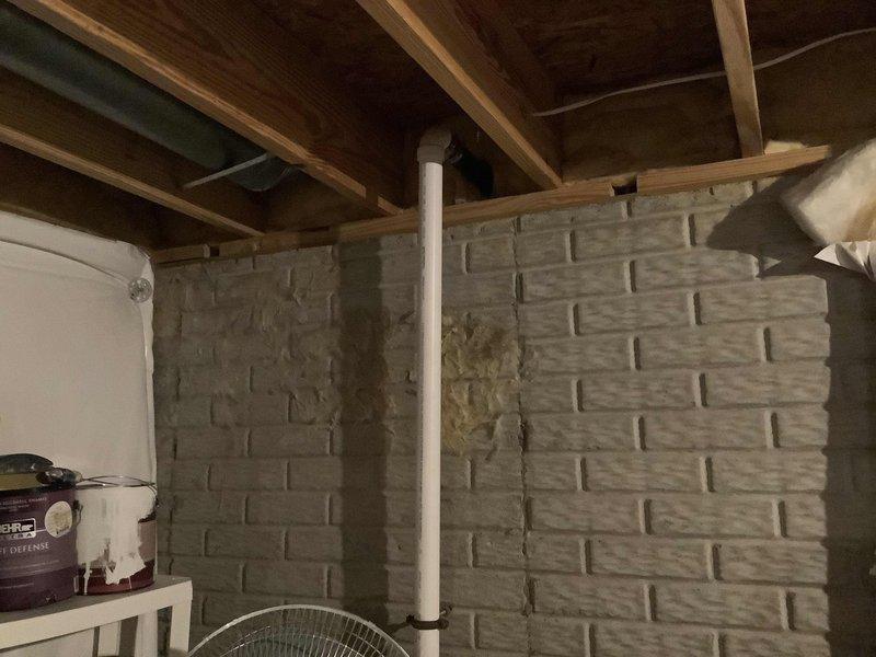Responded to water leak originating from piping at rear of residence. Upon arrival, conducted thorough inspection of affected area including basement/crawl space where plumbing system was accessible. Located source of leak in PVC piping system running through the structure. Documented existing conditions with photographs showing exposed joists, concrete block walls, and vertical PVC pipe runs. Assessed water damage and placed fan for drying purposes. Completed initial diagnostic evaluation and provided recommendations for repair.