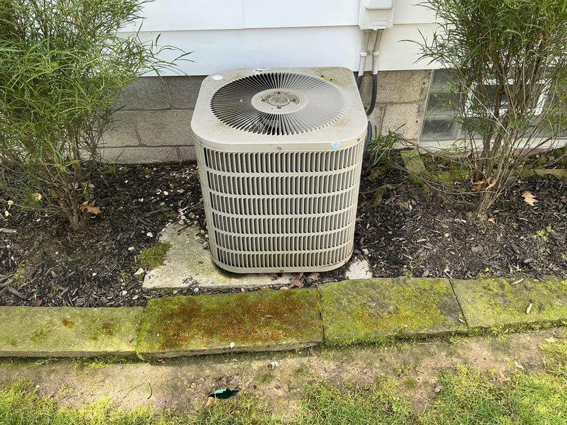 Conducted on-site assessment of 22-year-old residential air conditioning system for replacement estimate. Evaluated existing outdoor condenser unit with cylindrical design and horizontal fin configuration positioned on concrete pad against building exterior, noting age-related wear and system inefficiency. Inspected attic-mounted ductwork system, documenting metal duct routing through ceiling joists and assessing overall HVAC infrastructure condition to provide comprehensive replacement recommendations.
