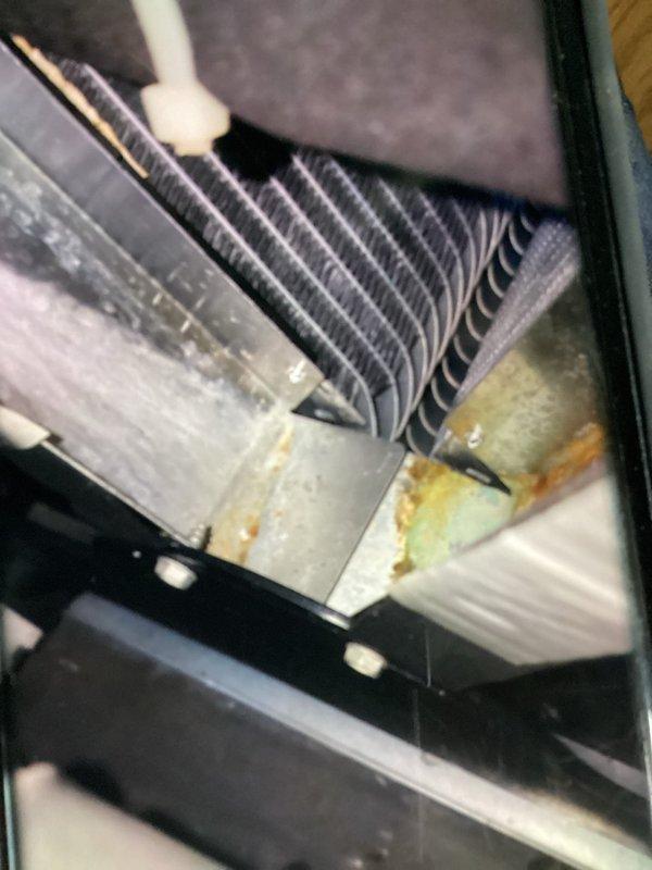 Completed MVP recurring cooling maintenance visit on residential HVAC system. Inspected evaporator coil assembly and found unit operational with intact coil fins, though housing showed signs of age-related corrosion and moisture staining on metal surfaces. Documented airflow direction markings and current equipment condition with photographic evidence for service records.