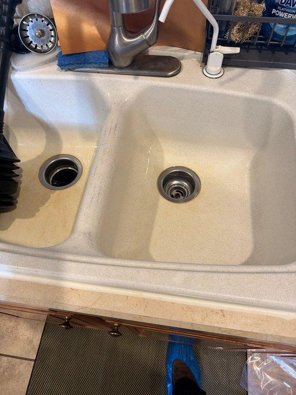 Responded to kitchen drain clog in double-basin sink where homeowner's previous attempts at clearing the blockage were unsuccessful. Upon arrival, found standing water with discolored, murky appearance in the right basin, indicating significant drainage obstruction. Assessed the plumbing system and determined the blockage location within the drain line. Utilized appropriate drain cleaning equipment and techniques to remove the clog, restoring proper water flow and drainage function to both basins. Tested the system to verify complete clearance and proper operation of the drain assembly. Documented conditions with photographs showing before and after states of the drainage issue.