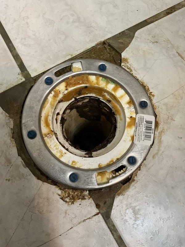 Responded to a toilet repair request in a 50-year-old home where the homeowner reported issues requiring a new wax ring and seal. Upon arrival, inspected the toilet installation and surrounding plumbing infrastructure, including overhead drain piping and floor drain connections. Documented existing conditions showing aged plumbing components with visible corrosion, staining, and mineral deposits on metal fixtures, indicating long-term water exposure and potential seal deterioration that would affect toilet performance and stability.