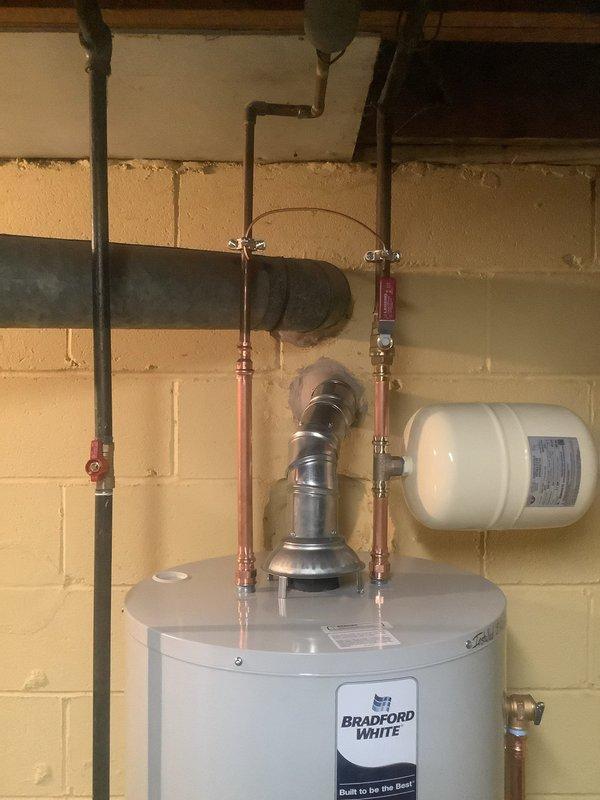 Installed a new 50-gallon Bradford White water heater with 6-year manufacturer warranty in basement utility room. Replaced existing flex lines with copper piping, installed new ball valve on cold water line, and mounted new thermal expansion tank on wall. Upgraded gas line connections by removing old grease valve and appliance whip, installing new gas shut-off valve for improved safety and code compliance. Properly vented unit through existing exhaust system to ceiling, verified all plumbing connections for leaks, and removed old water heater from premises upon completion.