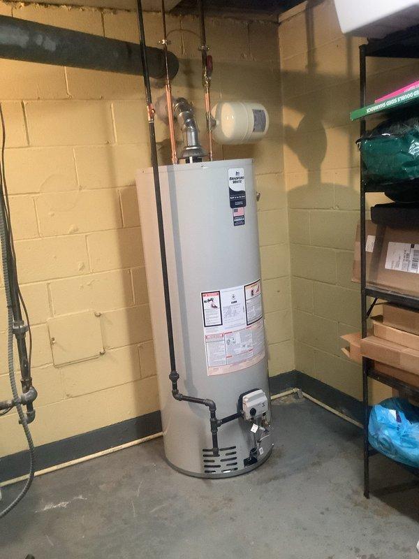 Installed a new 50-gallon Bradford White water heater with 6-year manufacturer warranty in basement utility room. Replaced existing flex lines with copper piping, installed new ball valve on cold water line, and mounted new thermal expansion tank on wall. Upgraded gas line connections by removing old grease valve and appliance whip, installing new gas shut-off valve for improved safety and code compliance. Properly vented unit through existing exhaust system to ceiling, verified all plumbing connections for leaks, and removed old water heater from premises upon completion.
