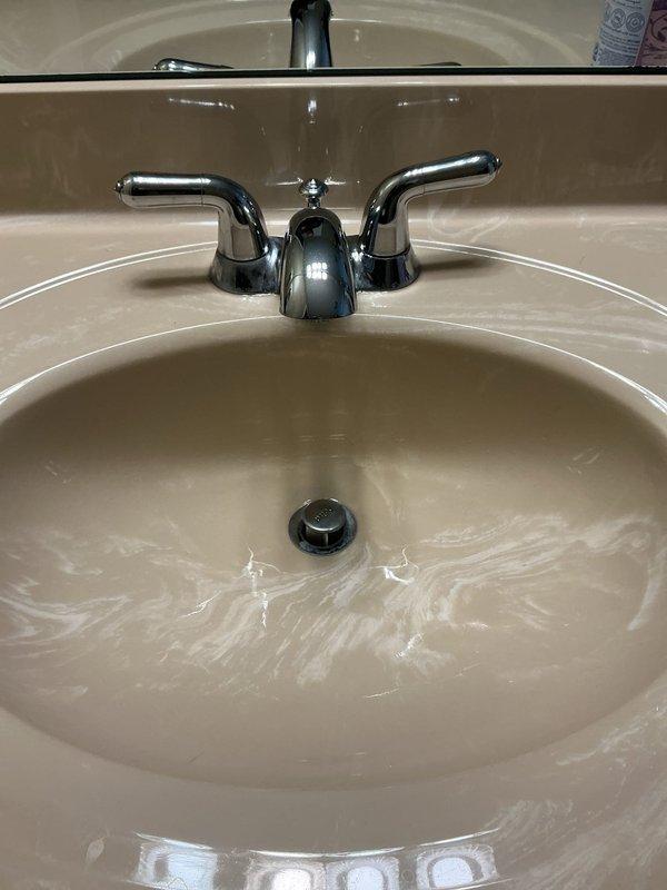 Responded to service call for multiple plumbing issues including sump pump discharge pipe leak, leaking kitchen and bathroom faucets, and faucet installation request. Upon inspection, assessed the sump pump discharge connection for source of leak and evaluated condition of kitchen double-basin sink faucet and bathroom sink faucet, both showing signs of wear and active leaking. Documented existing fixtures with photos showing chrome kitchen faucet with spray attachment and two-handle chrome bathroom faucet. Provided recommendations for repair or replacement of leaking fixtures and discussed faucet installation in additional bathroom using customer-supplied parts.