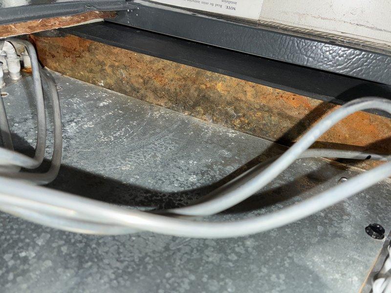 Completed scheduled maintenance visit on a 5-year-old cooling system. Inspected air handling unit interior, noting dust accumulation on filter media and insulation surfaces. Observed rust formation on metal access panel and mineral deposit buildup in condensate drain system. Verified refrigerant line connections and cleared drain line obstruction to restore proper condensate flow and prevent potential water damage.