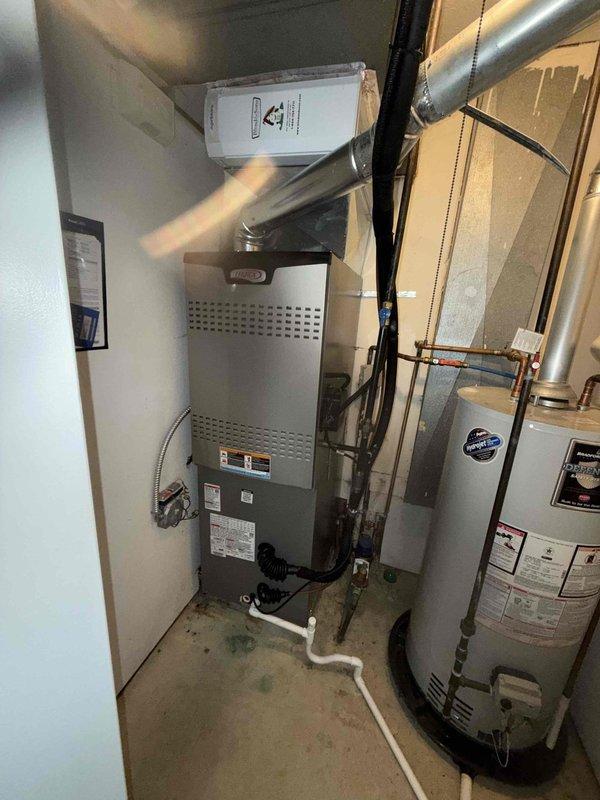 Performed comprehensive air conditioning tune-up on residential HVAC system located in mechanical closet. Inspected control board and DIP switch configurations, verified all electrical connections and wiring integrity, and evaluated overall system operation. Documented equipment condition with photos showing furnace, water heater, ductwork, and control components all functioning properly with no immediate service needs identified.