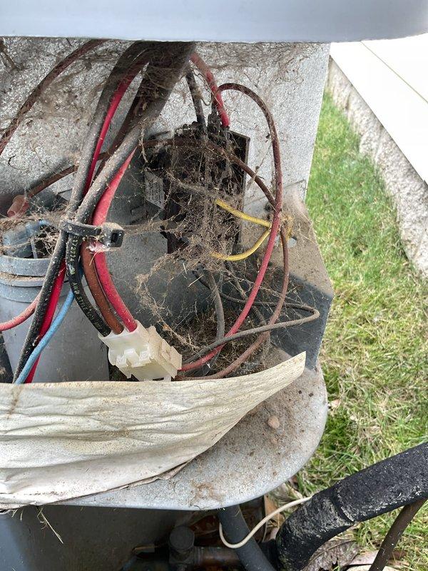 Responded to service call for 20-year-old air conditioning system failing to reach thermostat setpoint. Performed diagnostic testing using manifold gauges to check refrigerant pressures and system performance. Upon inspection, discovered outdoor condensing unit interior heavily contaminated with dirt, debris, spider webs, and organic material buildup affecting system efficiency. Electrical connections showed signs of age and environmental exposure. System is operational but operating below optimal capacity due to age and lack of preventative maintenance, resulting in insufficient cooling output to satisfy thermostat demand.