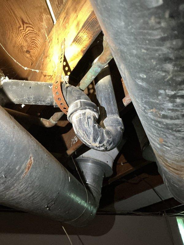 Responded to a clogged bathtub with drainage backup from the bathroom sink. Upon inspection, found standing water in the tub and confirmed that sink usage was causing wastewater to back up into the bathtub, indicating a blockage in the shared drain line. Accessed the drain system through the crawlspace/ceiling area below the bathroom and inspected the P-trap and waste piping assembly. Cleared the obstruction from the drainage system, restoring proper flow through both the sink and tub drains. Verified that water now drains freely from both fixtures without backup. System is functioning normally.