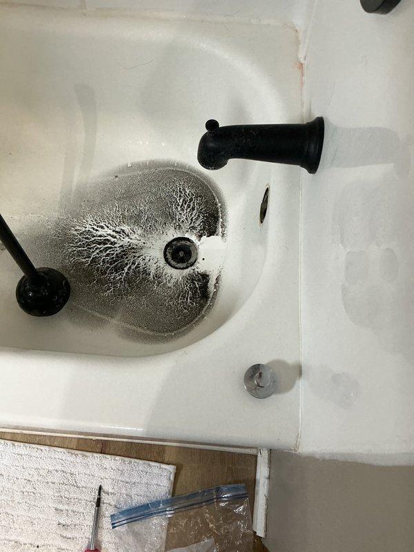 Responded to a clogged bathtub with drainage backup from the bathroom sink. Upon inspection, found standing water in the tub and confirmed that sink usage was causing wastewater to back up into the bathtub, indicating a blockage in the shared drain line. Accessed the drain system through the crawlspace/ceiling area below the bathroom and inspected the P-trap and waste piping assembly. Cleared the obstruction from the drainage system, restoring proper flow through both the sink and tub drains. Verified that water now drains freely from both fixtures without backup. System is functioning normally.
