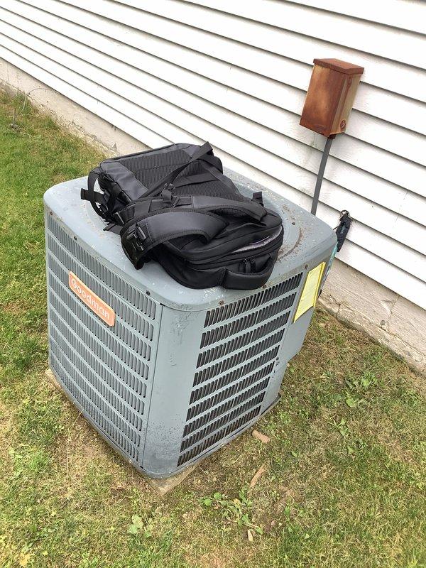 Conducted comprehensive site assessment for complete HVAC system replacement including air conditioning condenser unit and air handler located in attic space. Evaluated existing Goodman outdoor condenser unit, electrical disconnect box with visible weathering and oxidation, refrigerant line set, and condensate drainage system with safety switch. Accessed attic-mounted air handler through interior closet using customer-provided ladder to assess ductwork configuration, clearances, and installation requirements. Documented existing equipment conditions, electrical service connections including conduit routing and ground-level wiring terminations, and concrete pad placement. Photographed all system components and utility connections to develop accurate replacement specifications and provide detailed estimate for new equipment installation.