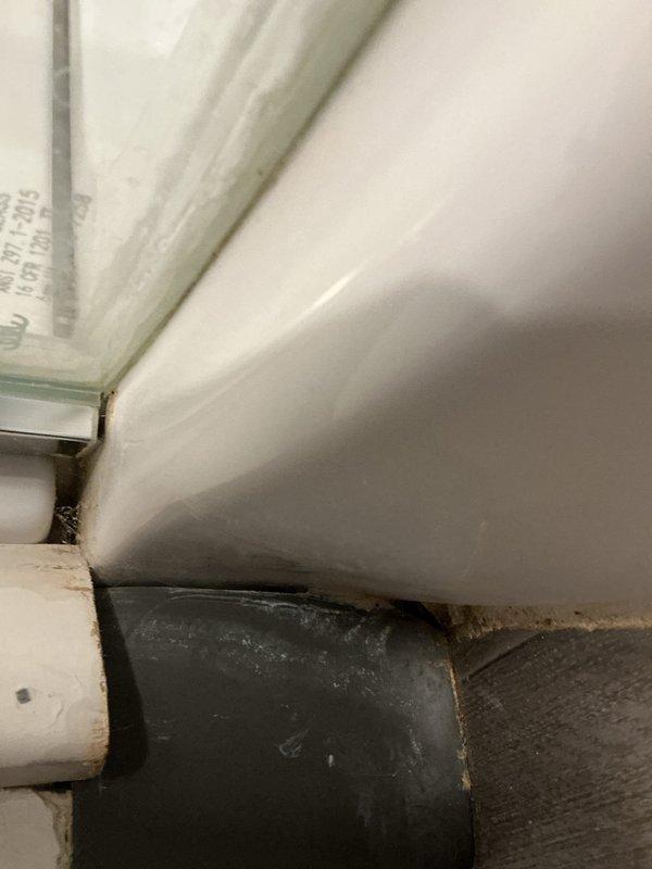 Responded to service call for reported shower leak. Upon inspection, identified moisture infiltration at shower enclosure corner joint with visible water staining and discoloration along wall-to-floor seam. Examined Delta shower fixture installation and surrounding plumbing connections. Documented deteriorated caulking and seal failure at corner junction where vertical supply line meets the enclosure, allowing water to escape during shower use. Assessed exposed piping for additional leak sources and confirmed primary issue at compromised sealant joint requiring re-caulking and potential trim adjustment to prevent future water damage.
