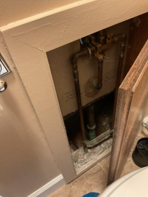 Responded to service call for odor emanating from garage floor drain and leaky faucet. Upon inspection, accessed interior plumbing through wall cavity to investigate drainage system and identified source of malodor from garage drain. Inspected copper supply lines and connections during wall access for the reported faucet leak. Examined exterior garage floor drain with rusted cover at concrete slab intersection and addressed drainage concerns to eliminate odor issue.