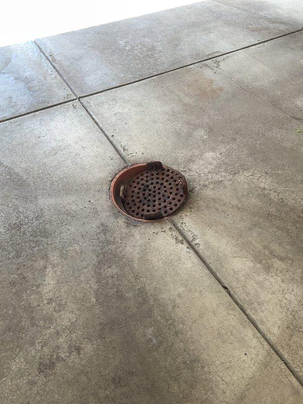 Responded to service call for odor emanating from garage floor drain and leaky faucet. Upon inspection, accessed interior plumbing through wall cavity to investigate drainage system and identified source of malodor from garage drain. Inspected copper supply lines and connections during wall access for the reported faucet leak. Examined exterior garage floor drain with rusted cover at concrete slab intersection and addressed drainage concerns to eliminate odor issue.