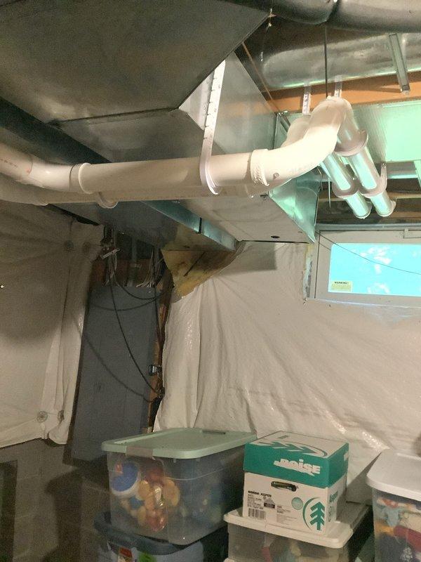 Completed installation of a 90% efficiency furnace and air conditioning system in basement location. Installed new air handler unit suspended from ceiling joists with proper support, connected to new ductwork system including large-diameter supply trunk lines. Configured PVC condensate drainage system with multiple elbows and joints to route condensate away from equipment according to code requirements. Ran white PVC venting pipes from furnace through building structure for proper combustion air intake and exhaust. Installed all necessary electrical connections and control wiring to air handler and outdoor condensing unit. System tested and verified operational with proper airflow and drainage confirmed.