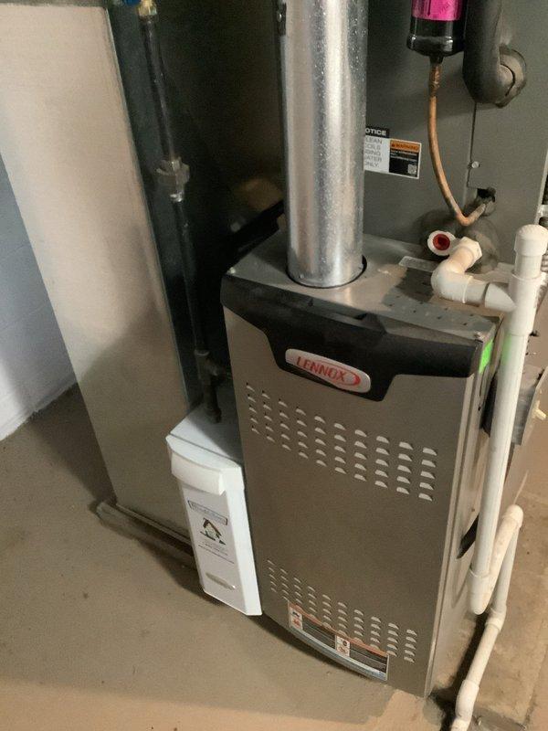 Completed comprehensive MVP cooling maintenance visit on residential Lennox HVAC system. Inspected indoor furnace unit in basement utility area, verifying proper operation of all components, ductwork connections, and associated plumbing including condensate drainage system. Examined outdoor condenser unit, noting vegetation encroachment around equipment that may restrict airflow; documented unit condition and operational status. System photographed for service records showing both indoor and outdoor equipment in functional condition.