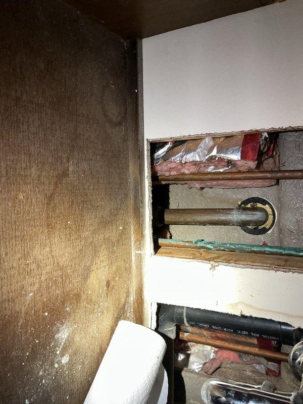 Responded to clogged bathtub drain on upper level. Accessed plumbing system through existing wall cavity to diagnose blockage. Removed wall access panel to inspect vertical copper water lines and drainage system. Cleared obstruction from bathtub drain assembly, including overflow drain mechanism. Verified proper water flow through tub spout and drain. Restored functionality to bathtub fixture and plumbing components.