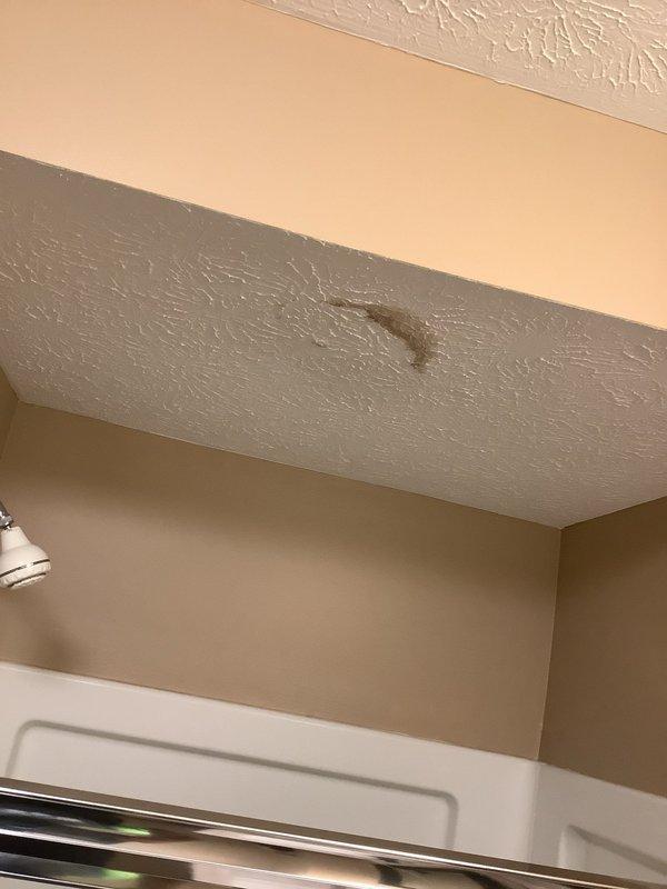 Responded to water leak complaint with visible ceiling damage above basement shower area. Upon investigation, identified condensation forming on exposed ductwork in unconditioned basement space, causing moisture to drip onto ceiling below and create water staining. Ductwork lacked proper insulation, allowing warm, humid air to contact cold supply duct surfaces during cooling operation, resulting in sweating condition. Documented existing water damage to ceiling with photographic evidence showing brown discoloration and moisture penetration. Explained condensation issue to homeowner and recommended insulating exposed ductwork with appropriate R-value duct wrap to prevent future sweating and moisture damage.
