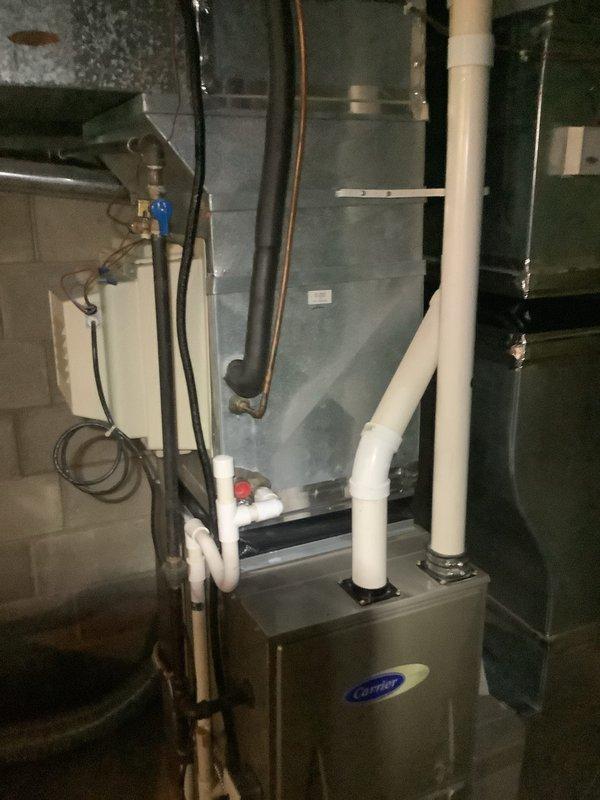 Completed installation of new air conditioning system including outdoor condenser unit and indoor evaporator coil. Outdoor condenser unit was positioned on existing concrete pad against building exterior with proper electrical disconnect and refrigerant line connections. Indoor evaporator coil was installed in conjunction with existing Carrier air handler unit in basement mechanical room. Refrigerant lines were run between outdoor and indoor components, properly insulated and secured along building exterior and through basement. System was evacuated, charged to manufacturer specifications, and tested for proper operation. All electrical connections were completed per code requirements, condensate drain lines were installed and verified for proper drainage, and system airflow was confirmed. Unit was started up successfully and left in operational condition.