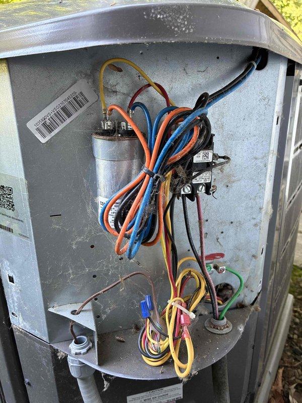 Completed BS-MVP cooling maintenance visit on ground-level AC unit, 2 years old. Opened exterior cabinet and inspected internal electrical components including dual-run capacitor, contactor, and associated wiring connections. All electrical connections secure with proper wire management and zip ties in place. Observed moderate dust and debris accumulation on interior surfaces and bottom of cabinet, typical for outdoor installation. Inspected condenser coil and found significant dust, dirt, and fibrous debris buildup on fins and filter media, restricting airflow. Cleaned coil surfaces to restore proper air circulation and system efficiency. Verified capacitor terminals and wiring color codes for proper configuration. All manufacturer labels and QR codes intact and legible for future reference. Unit operational and functioning within normal parameters following maintenance procedures.