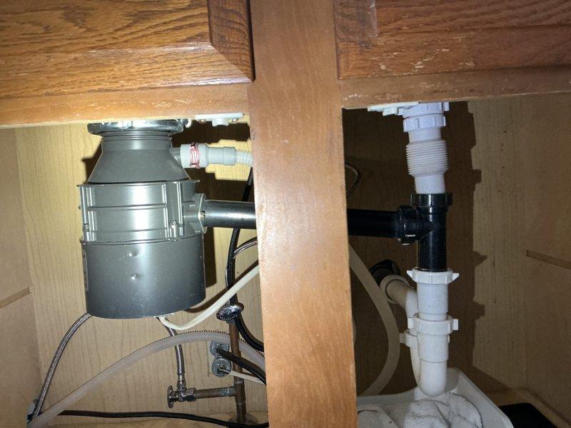 Responded to service call for garbage disposal malfunction and drainage backup issue where kitchen waste water containing food debris was backing up into the bathroom tub. Upon inspection, identified faulty garbage disposal unit beneath kitchen sink and confirmed drainage system obstruction causing cross-contamination between fixtures. Assessed under-sink plumbing configuration including PVC trap assembly and disposal mounting. Repaired garbage disposal unit, addressing mechanical failure and ensuring proper electrical connection and mounting integrity. Cleared blockage in drain line that was causing wastewater to travel from kitchen drain into bathroom plumbing. Verified proper drainage flow from kitchen sink through disposal and confirmed elimination of backup into tub. Tested disposal operation for proper grinding function and verified all connections for leaks. System restored to full functionality with proper drainage throughout affected plumbing fixtures.