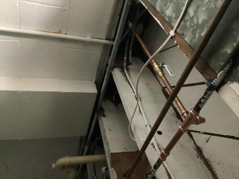 Responded to emergency call for burst cold water line supplying outdoor spigot. Upon arrival, found homeowner had shut off main water supply to stop active flooding. Accessed affected piping in basement/crawlspace area where copper supply line had failed. Assessed damage to water line and surrounding infrastructure, including proximity to HVAC ductwork and ceiling joists. Documented existing plumbing configuration showing multiple copper lines, insulated piping, and connection points. Evaluated extent of water damage to ceiling materials and structural components. Provided diagnostic assessment of failed pipe section and recommended repair options to restore water service to the property.