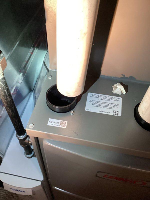 Responded to report of condensation water accumulation around exhaust pipe on newly installed furnace (less than two weeks in service). Upon arrival, inspected furnace installation and exhaust venting system. Observed water staining and moisture present on white PVC exhaust pipe extending from top of unit. Verified exhaust pipe penetration through roof deck and confirmed proper pipe slope for condensate drainage. Inspected exhaust termination point and intake venting configuration. Checked condensate drain system, trap assembly, and drain line routing for proper installation and function. Examined furnace combustion system and heat exchanger operation to rule out internal condensation issues. Documented conditions with photographs showing exhaust pipe staining and overall installation layout. System operating within normal parameters with no safety concerns identified at time of inspection.