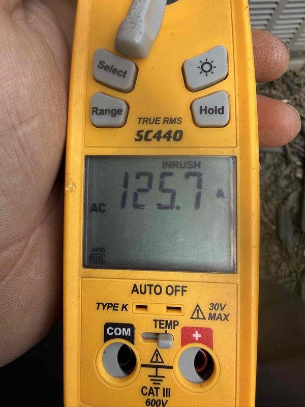 Completed MVP cooling maintenance visit and diagnosed evaporator coil with significant frost buildup indicating restricted airflow or low refrigerant charge. Measured inrush amperage at 125.7A using digital multimeter to assess compressor performance and electrical operation. Documented system conditions with photos showing extensive ice accumulation on evaporator fins and blower assembly for service records.