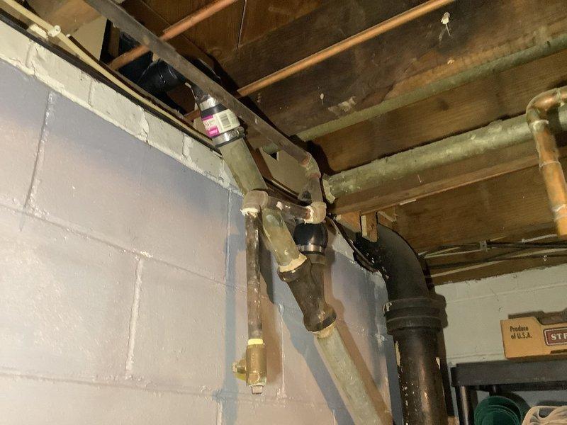 Responded to service call for water heater replacement estimate and water leak investigation. Assessed existing plumbing infrastructure in basement utility area, documenting aged copper piping system and mechanical components. Identified active water leak originating from ceiling, traced source to upstairs bathroom toilet with failed wax ring seal. Inspected bathroom toilet installation, confirmed deteriorated wax ring causing water infiltration through floor into basement below. Provided estimate for electric water heater replacement and recommended immediate toilet wax ring replacement to prevent further water damage to ceiling structure and building materials.