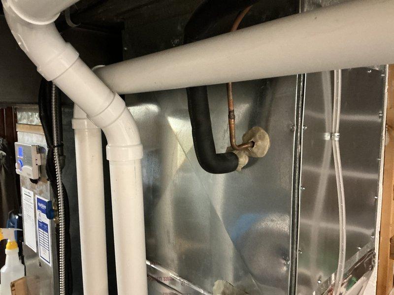 Completed on-site assessment of 10-year-old Lennox air conditioning system experiencing refrigerant leak. Inspected outdoor condensing unit positioned on concrete pad alongside residence and evaluated indoor evaporator coil assembly with associated PVC condensate drain lines and copper refrigerant piping. Documented equipment condition through photographs and provided replacement estimate for complete HVAC system due to age of existing equipment and cost-effectiveness of replacement versus repair.