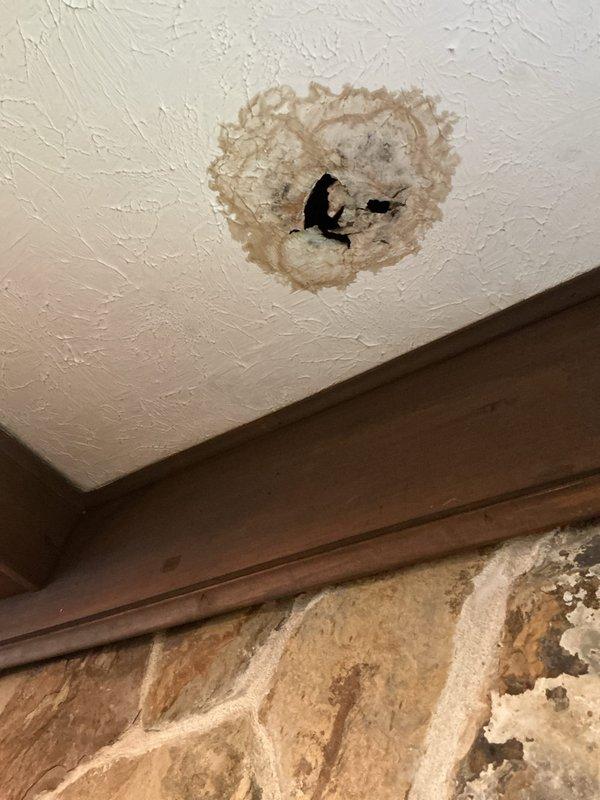 Responded to a plumbing emergency involving water leaking from the base of a toilet that was seeping through the floor and causing significant water damage to the ceiling below. Upon inspection, identified a failed wax ring seal at the toilet base, removed and reset the toilet with a new wax ring and closet bolts, and verified proper seal and stability. Documented extensive water damage to the bathroom floor tiles (visible cracking) and ceiling damage in the room below, including water staining, structural deterioration, and compromised drywall requiring future remediation by appropriate trades.