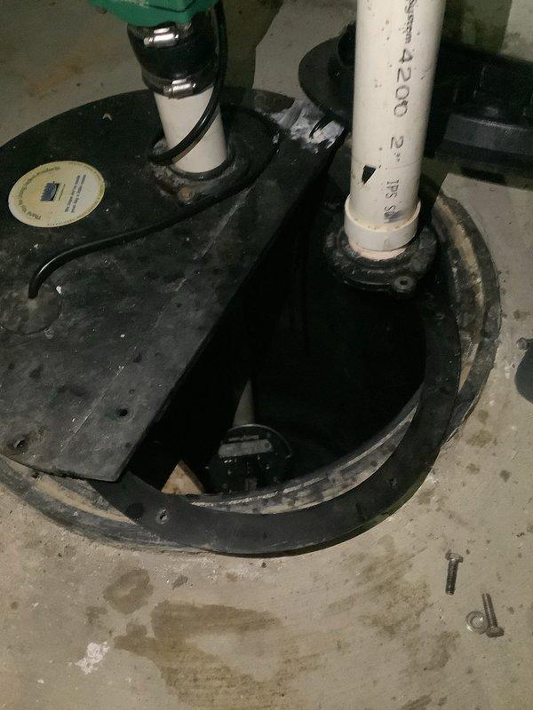 Responded to service call for non-operational sump pump system originally installed in 2022. Upon arrival, inspected the sump pump installation located in basement utility area. Removed sump pit cover to assess pump condition and water levels within the circular black basin. Observed standing water in pit with pump submerged and discharge piping connected via white PVC with fill line markings at 2.5 inches. Examined pump motor, float switch mechanism, and electrical connections for signs of failure or malfunction. Checked discharge line for proper flow and verified all piping connections including green valve component at top of system. Tested pump activation and cycle operation. Addressed warranty inquiry regarding parts and labor coverage, noting system is beyond the standard one-year warranty period for sump pump installations. Documented existing conditions with photographs showing pump basin, discharge piping configuration, and overall system setup. Provided assessment of pump fun