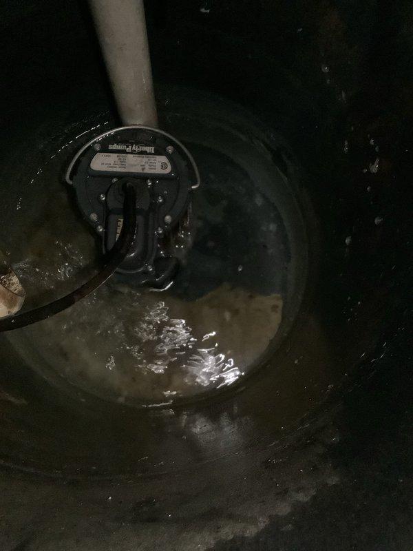 Responded to service call for non-operational sump pump system originally installed in 2022. Upon arrival, inspected the sump pump installation located in basement utility area. Removed sump pit cover to assess pump condition and water levels within the circular black basin. Observed standing water in pit with pump submerged and discharge piping connected via white PVC with fill line markings at 2.5 inches. Examined pump motor, float switch mechanism, and electrical connections for signs of failure or malfunction. Checked discharge line for proper flow and verified all piping connections including green valve component at top of system. Tested pump activation and cycle operation. Addressed warranty inquiry regarding parts and labor coverage, noting system is beyond the standard one-year warranty period for sump pump installations. Documented existing conditions with photographs showing pump basin, discharge piping configuration, and overall system setup. Provided assessment of pump fun