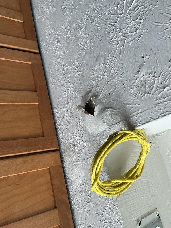 Responded to water leak report originating from ceiling in garage with suspected source in bathroom above. Upon investigation, accessed wall cavity to identify leak source. Created exploratory opening in drywall to expose plumbing lines and trace water infiltration path. Inspected exposed insulation and building materials for moisture damage and confirmed active leak location. Documented conditions with photographs for repair assessment and recommended necessary plumbing repairs to resolve water intrusion issue.