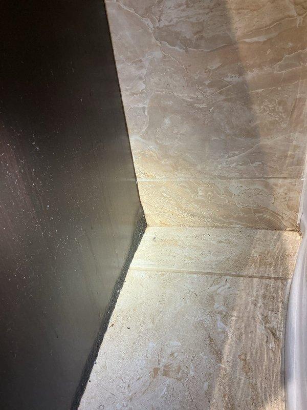Responded to water leak report originating from ceiling in garage with suspected source in bathroom above. Upon investigation, accessed wall cavity to identify leak source. Created exploratory opening in drywall to expose plumbing lines and trace water infiltration path. Inspected exposed insulation and building materials for moisture damage and confirmed active leak location. Documented conditions with photographs for repair assessment and recommended necessary plumbing repairs to resolve water intrusion issue.