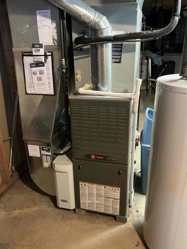Conducted on-site HVAC system evaluation for equipment replacement estimate in residential basement mechanical room. Assessed existing 12-year-old Trane furnace, air handler unit, and associated ductwork configuration. Documented current system layout including metallic supply ductwork, flexible return ducts, and equipment placement relative to water heater and utility infrastructure. Applied veteran discount to quoted replacement pricing and captured photographic documentation of existing equipment conditions for proposal reference.