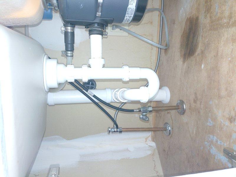 Replaced leaking 2" ABS drain piping under kitchen sink with new 2" PVC piping due to inaccessible original line that would have required extensive demolition to access. Abandoned existing ABS piping in place by capping at basement ceiling and at drain outlet in back of cabinet. Routed new PVC drain line through bottom of cabinet and installed escutcheon plate around pipe penetration. Replaced tubular drain assembly to garbage disposal unit and basket strainer with new components. Installed air admittance valve to address venting requirements for proper drain function.
