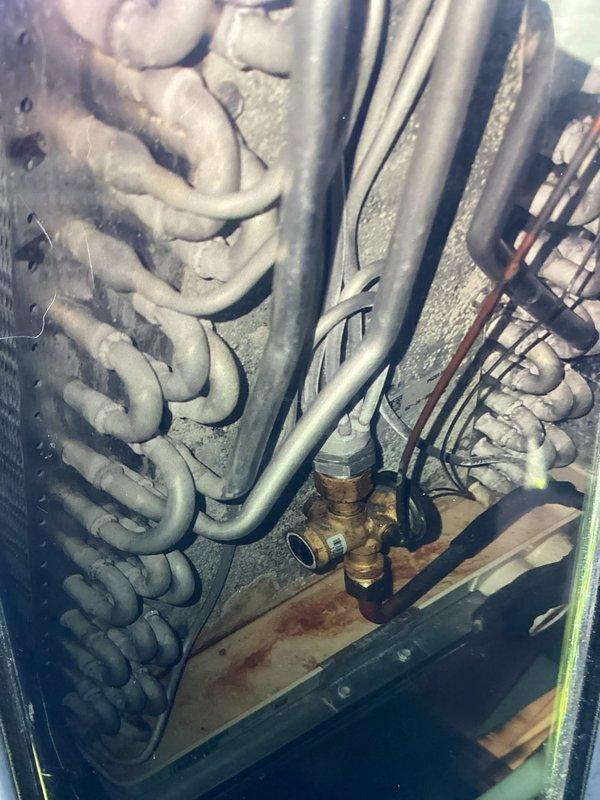 Completed MVP cooling maintenance visit and discovered heavy ice buildup on evaporator coil indicating system malfunction. Documented frosted coil condition with visible ice accumulation on copper tubing and condensation present on ductwork, suggesting possible airflow restriction, refrigerant issue, or drainage problem requiring further diagnosis and repair to restore proper cooling operation.