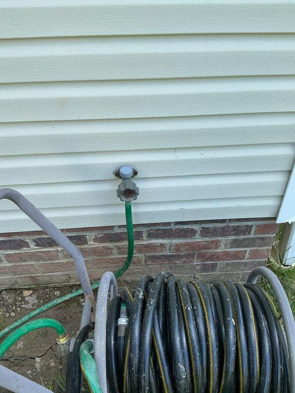 Conducted site evaluation for outdoor water spigot replacement and provided quote for frost-free hose bib installation. Assessed existing gray spigot mounted on vinyl siding with connected garden hoses and inspected corresponding interior plumbing connections in basement crawl space. Documented current configuration through exterior and interior photography to support installation proposal for upgraded frost-free spigot system.