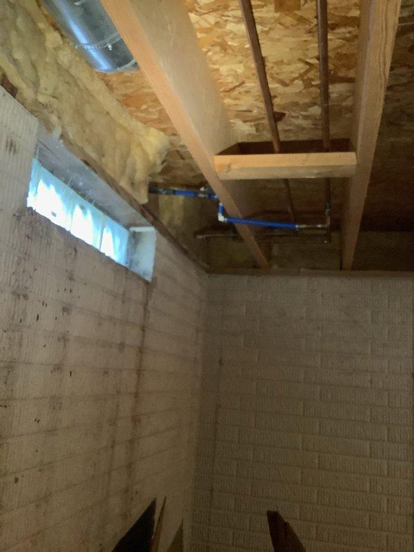 Responded to emergency call for severely leaking outdoor water spigot. Upon arrival, accessed basement area to locate and assess the damaged fixture and associated plumbing connections. The outdoor spigot had failed, causing significant water leakage that required immediate attention to prevent further water damage and waste.

Inspected the existing plumbing infrastructure in the unfinished basement area, identifying the blue PEX water supply lines and connections serving the exterior spigot. Evaluated the ceiling-mounted piping system, including the PEX lines with metal fittings and copper piping components running through the floor joists. Documented the condition of the installation area, noting the exposed wooden joists, insulation, and concrete block foundation walls for reference.

Shut off water supply to the affected line to stop the leak. Removed the damaged outdoor water spigot assembly and assessed the connection point for any additional damage or deterioration. Prepared the
