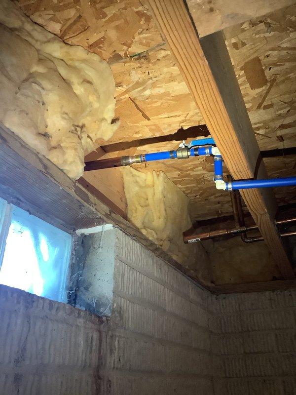 Responded to emergency call for severely leaking outdoor water spigot. Upon arrival, accessed basement area to locate and assess the damaged fixture and associated plumbing connections. The outdoor spigot had failed, causing significant water leakage that required immediate attention to prevent further water damage and waste.

Inspected the existing plumbing infrastructure in the unfinished basement area, identifying the blue PEX water supply lines and connections serving the exterior spigot. Evaluated the ceiling-mounted piping system, including the PEX lines with metal fittings and copper piping components running through the floor joists. Documented the condition of the installation area, noting the exposed wooden joists, insulation, and concrete block foundation walls for reference.

Shut off water supply to the affected line to stop the leak. Removed the damaged outdoor water spigot assembly and assessed the connection point for any additional damage or deterioration. Prepared the