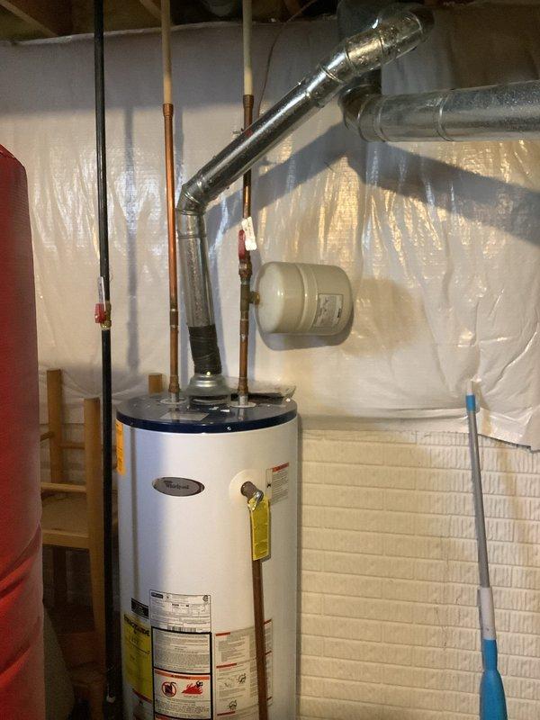 Responded to service call for knocking sound near waterlines and valve area. Upon inspection, examined main water meter assembly, shut-off valves, and associated copper piping mounted at wall. Assessed water heater installation including connected plumbing, expansion tank, and supply lines for potential sources of water hammer or loose components that could generate knocking sounds during water flow or pressure changes.