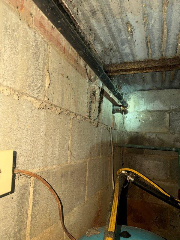 Conducted site assessment and provided quote for natural gas line replacement from meter to residence, spanning approximately 30 feet. Evaluated existing exterior gas meter assembly and piping configuration at foundation, noting weathered condition of current infrastructure. Inspected interior basement utility area where gas line enters structure, documenting corrugated metal ceiling conditions and existing pipe routing along concrete block walls. Photographed exterior meter installation showing aged piping and connections, as well as interior gas line entry point and distribution system. Determined potential need for complete meter replacement in addition to gas line installation based on current equipment condition and code compliance requirements.