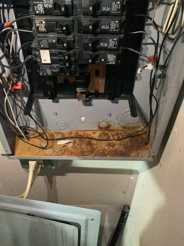 Responded to service call for fraying upper entrance electrical cable requiring replacement estimate. Upon inspection, discovered electrical panel with significant safety concerns including extensive rust and corrosion damage throughout the lower portion of the enclosure, indicating prolonged moisture exposure. The service entrance cable showed signs of deterioration with fraying conductors at the connection point. Panel contained multiple circuit breakers with dense wiring bundles entering from the top, with various colored conductors including black, red, white, yellow, and purple wires. The corrosion had compromised the integrity of the metal enclosure base plate where circuit breakers are mounted, creating potential safety hazards. Documented existing conditions with photographs showing the corroded panel box, deteriorated service entrance cable connections, and overall electrical system configuration. Provided comprehensive estimate for complete service entrance cable replacement 